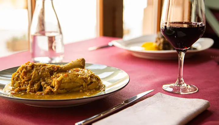 Plato de pollo de corral guisado con copa de vino